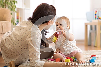 Adorable baby girl playing with educational toys in nursery. Child having fun with colorful different toys at home Stock Photo