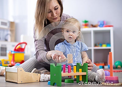 Adorable baby girl playing with educational toys in nursery. Happy healthy child having fun with colorful different toys Stock Photo