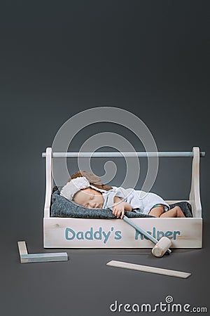 adorable baby with hammer in hand sleeping in wooden toolbox with daddys Stock Photo