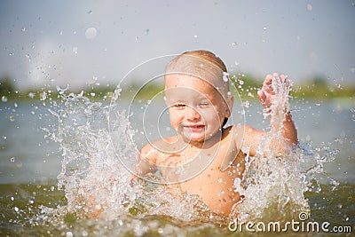 Adorable baby splashing water on lake beach Stock Photo