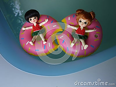 Adorable BJD Ball Joint Doll branded LATI in swimming suit. They`re ready to play water with colorful pool floats. Editorial Stock Photo