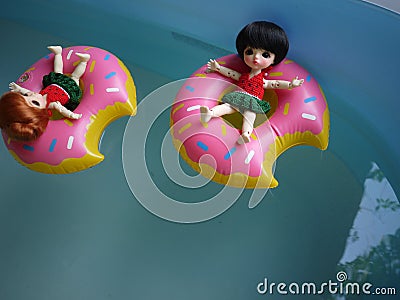 Adorable BJD Ball Joint Doll branded LATI in swimming suit. They`re ready to play water with colorful pool floats. Editorial Stock Photo