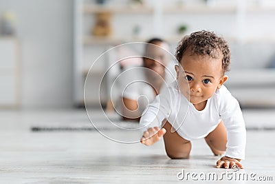 Adorable Black Infant Baby Crawling Away From Father At Home Stock Photo