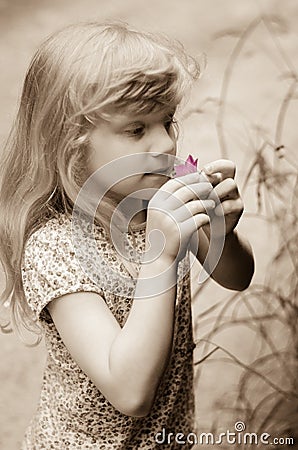 Adorable blond girl smelling pink flower Stock Photo