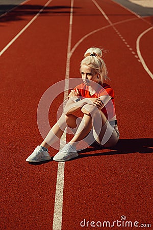 Adorable blonde sits on a jogging track Stock Photo