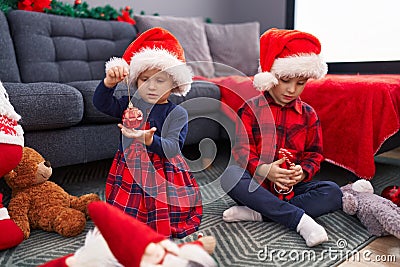 Adorable boy and girl celebrating christmas holding candies and decoration ball at home Stock Photo