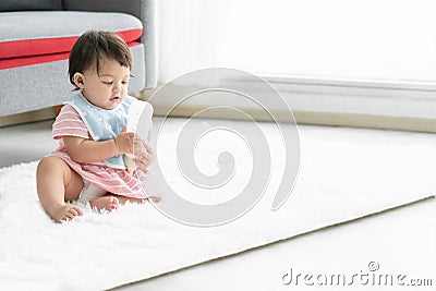 Adorable Caucasian little toddler baby girl wear apron, pink dress and diaper holding bottle milk in hands Stock Photo