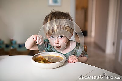 Adorable caucasian toddler boy eating healthy soup in the kitch Stock Photo