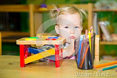 Adorable child girl playing with educational toys in nursery room. Kid in kindergarten in Montessori preschool class. Stock Photo