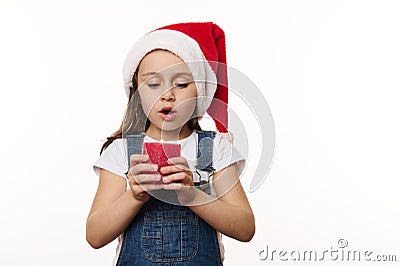 Adorable child, happy baby girl in Santa hat, makes cherished wish for Christmas, blows out a candle, isolated on white Stock Photo