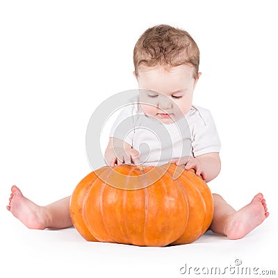 Adorable curious baby girl playing with big pumpkin Stock Photo