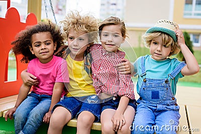 adorable curly boy embracing two multicultural children Stock Photo