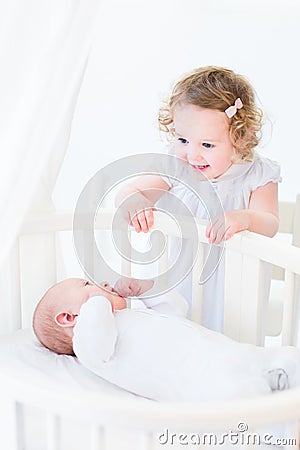 Adorable curly toddler girl talking to newborn brother Stock Photo