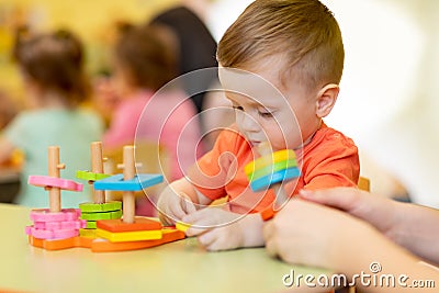 Adorable cute baby boy plays with educational sorter toys at kindergarten or nursery. Healthy happy toddler child Stock Photo