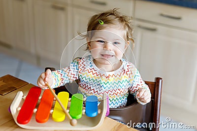 Adorable cute beautiful little baby girl playing with educational wooden music toys at home or nursery Stock Photo