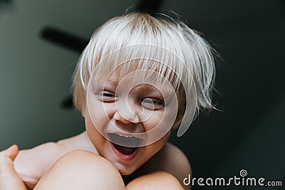 Adorable Cute Little Long Blonde Haired Blue Eyed Toddler Kid Boy Face Expressions Head Shots at Home Playing with Mom Stock Photo