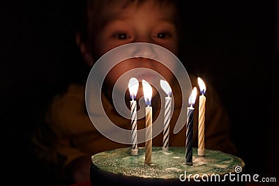Adorable five year old kid celebrating his birthday and blowing candles on homemade baked cake, indoor. Birthday party Stock Photo