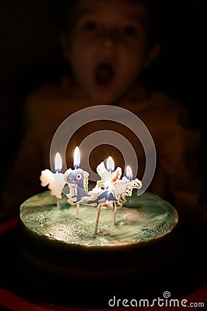 Adorable five year old kid celebrating his birthday and blowing candles on homemade baked cake, indoor. Birthday party Stock Photo