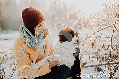 Adorable fluffy cute black and white border colly being trained and petting girl in a park. lights and bushes on the Stock Photo