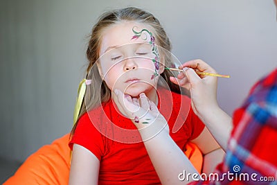 Adorable girl getting her face flower painted Stock Photo