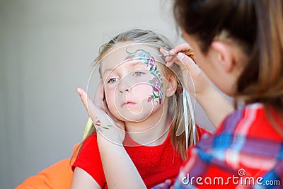 Adorable girl getting her face flower painted Stock Photo