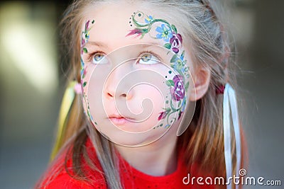 Adorable girl getting her face flower painted Stock Photo