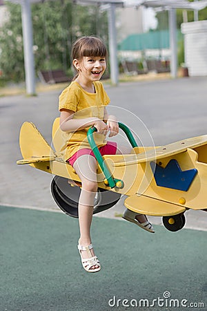 Little girl laughs and rolls on a seesaw on a playground Stock Photo