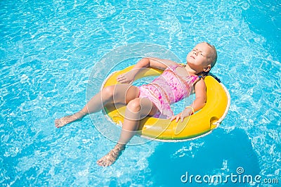 Adorable girl relax on yellow life ring in pool at protical beach resort Stock Photo