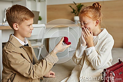 Adorable kids in love, boy make proposal to redhead girl Stock Photo