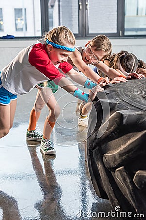 Adorable kids in sportswear training with tire at fitness studio Stock Photo