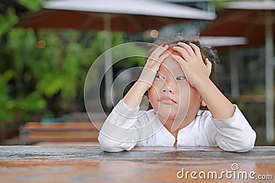 Adorable little Asian child girl expressed disappointment or displeasure on the wood table with looking out Stock Photo