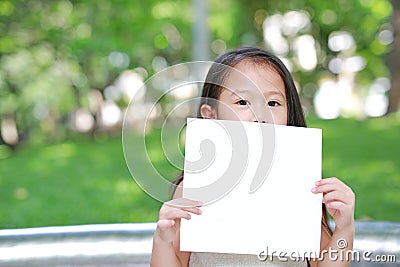 Adorable little Asian child girl holding up a blank white paper Stock Photo