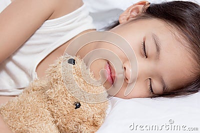 Adorable little Asian girl sleep on her bed with bear doll Stock Photo