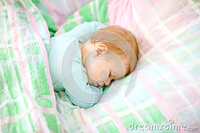 Lovely little baby girl sleeping in bed. Calm peaceful child dreaming during day sleep. Beautiful baby in parents bed Stock Photo