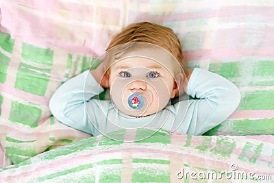 Adorable little baby girl after sleeping in bed. Calm peaceful child with a pacifier or dummy Stock Photo