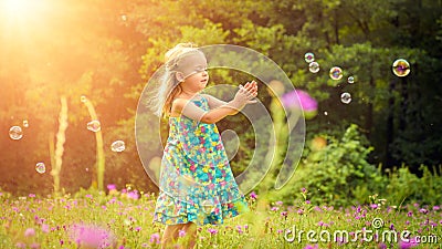 Adorable little blond girl having fun playing with soap bubbles Stock Photo