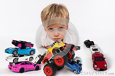 Adorable little boy lying all surrounded by car toys with his cute cheeks and lips ready to kiss someone Stock Photo