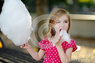 Adorable little girl eating candy-floss outdoors Stock Photo