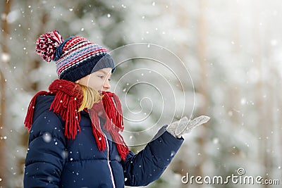 Adorable little girl having fun in beautiful winter park. Cute child playing in a snow. Stock Photo