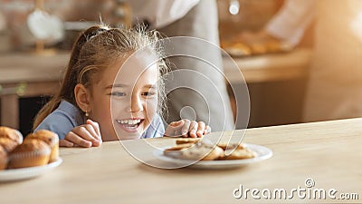 Adorable little girl looking at cookies with desire Stock Photo