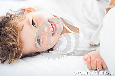 Adorable little girl lying in the bed and smiling in the early morning Stock Photo