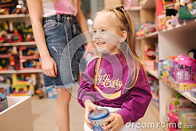 Adorable little girl with mom shopping for toys. Cute female in toy store. Happy young girl selecting toy Stock Photo