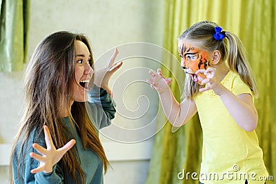 Adorable little girl painted like tiger playing with animator Stock Photo