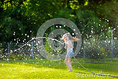 Adorable little girl playing with a garden hose Stock Photo