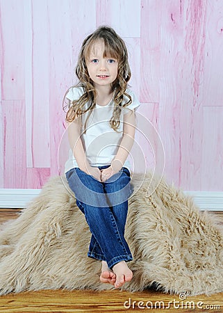 Adorable little girl posing on brown fur rug Stock Photo