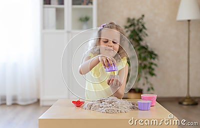 Adorable little girl sculpts cupcakes from kinetic sand. Stock Photo