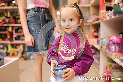 Adorable little girl with mom shopping for toys. Cute female in toy store. Happy young girl selecting toy Stock Photo