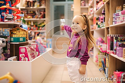 Adorable little girl shopping for toys. Cute female in toy store. Happy young girl selecting toy Stock Photo