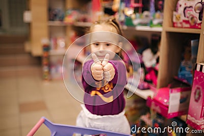 Adorable little girl shopping for toys. Cute female in toy store. Happy young girl selecting toy Stock Photo