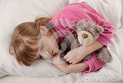 Adorable little girl sleeping in the bed with her toy Stock Photo